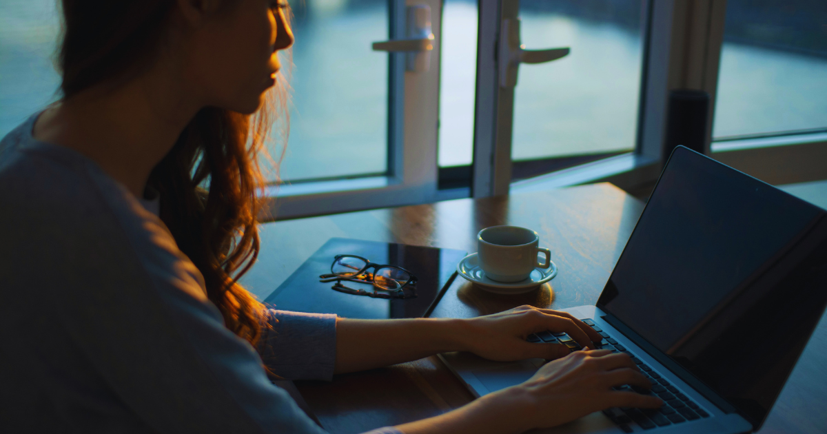 Woman over 35 focused at her laptop with morning coffee.