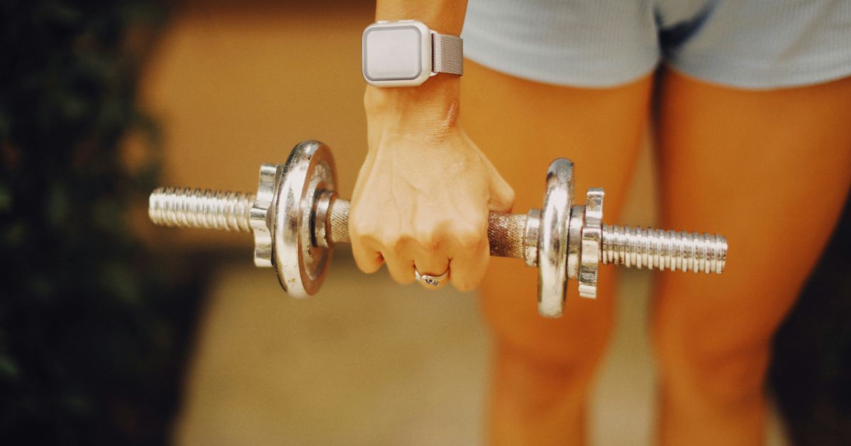 Person holding a dumbbell during a workout, representing strength training to prevent muscle loss after 35.